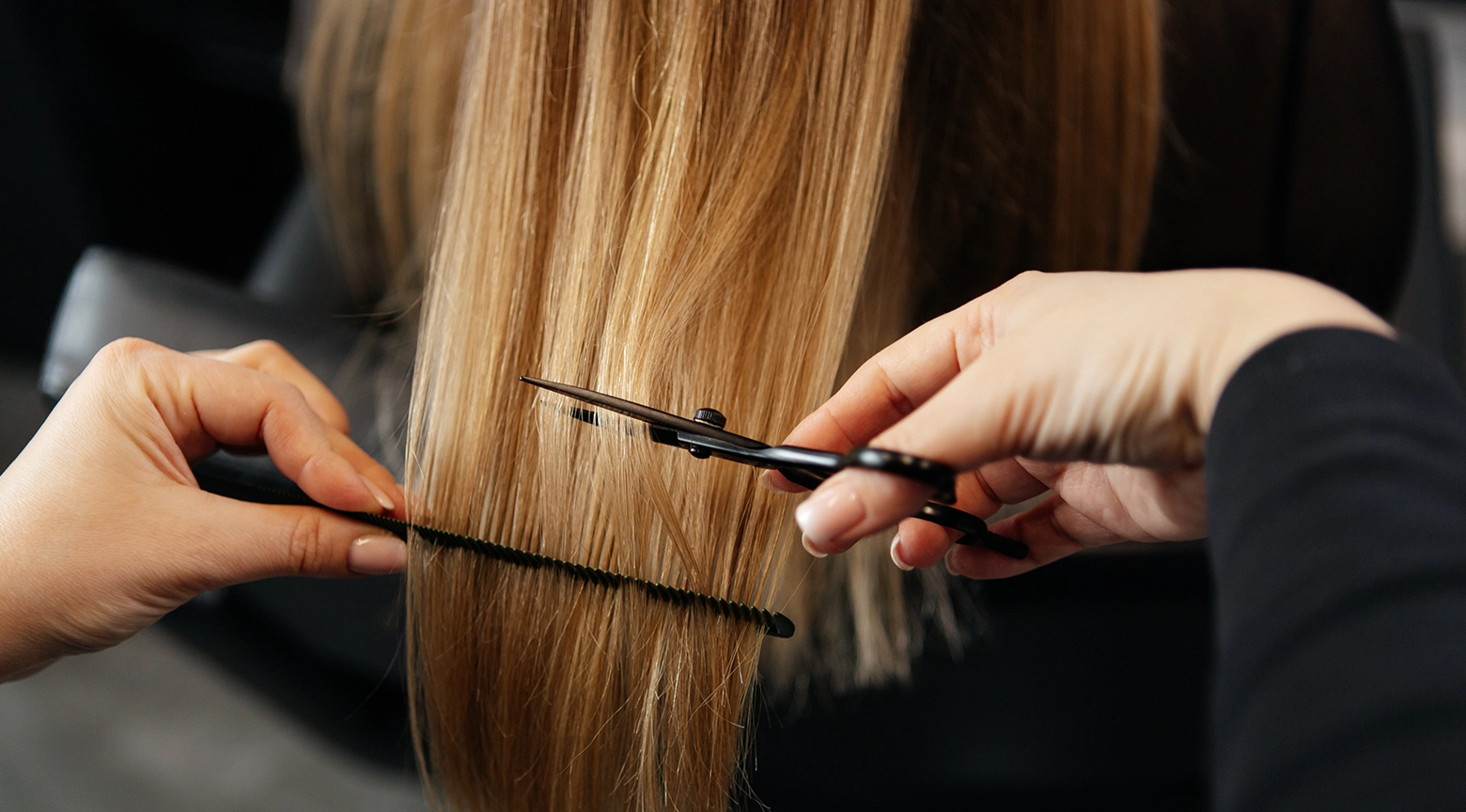Estilista cortando las puntas del cabello con tijeras y peine en un salón.