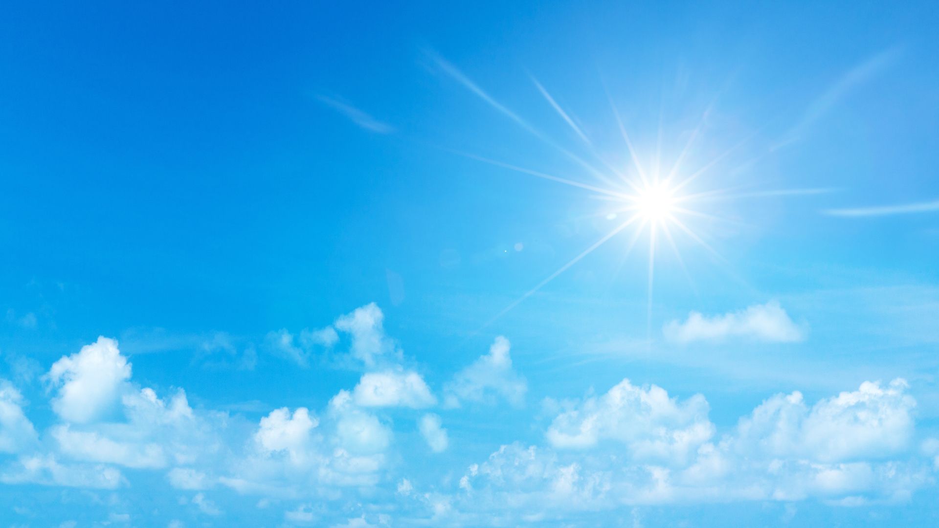 Sol brillante en un cielo azul con algunas nubes dispersas.