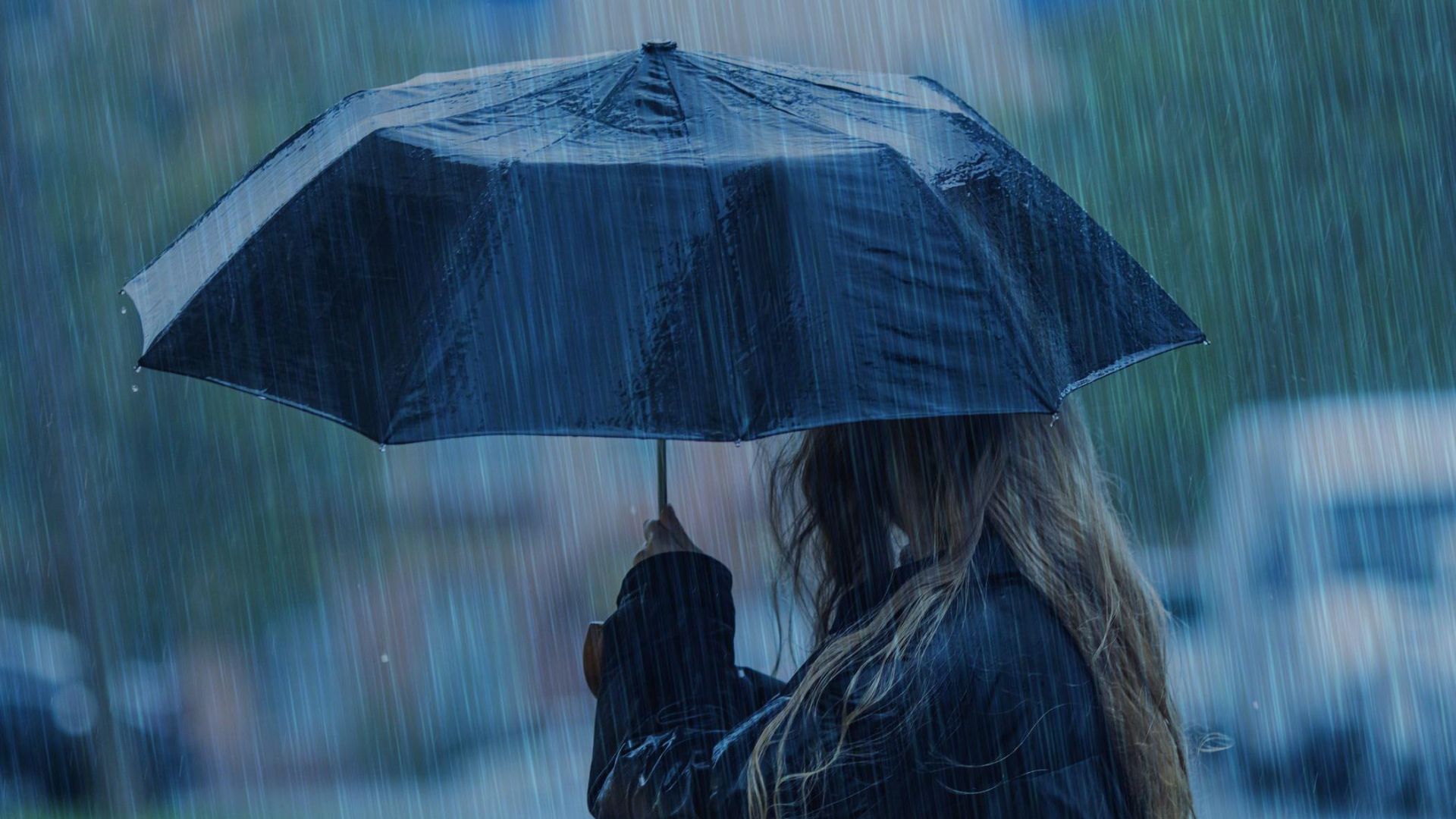 Persona sosteniendo un paraguas bajo una fuerte lluvia.