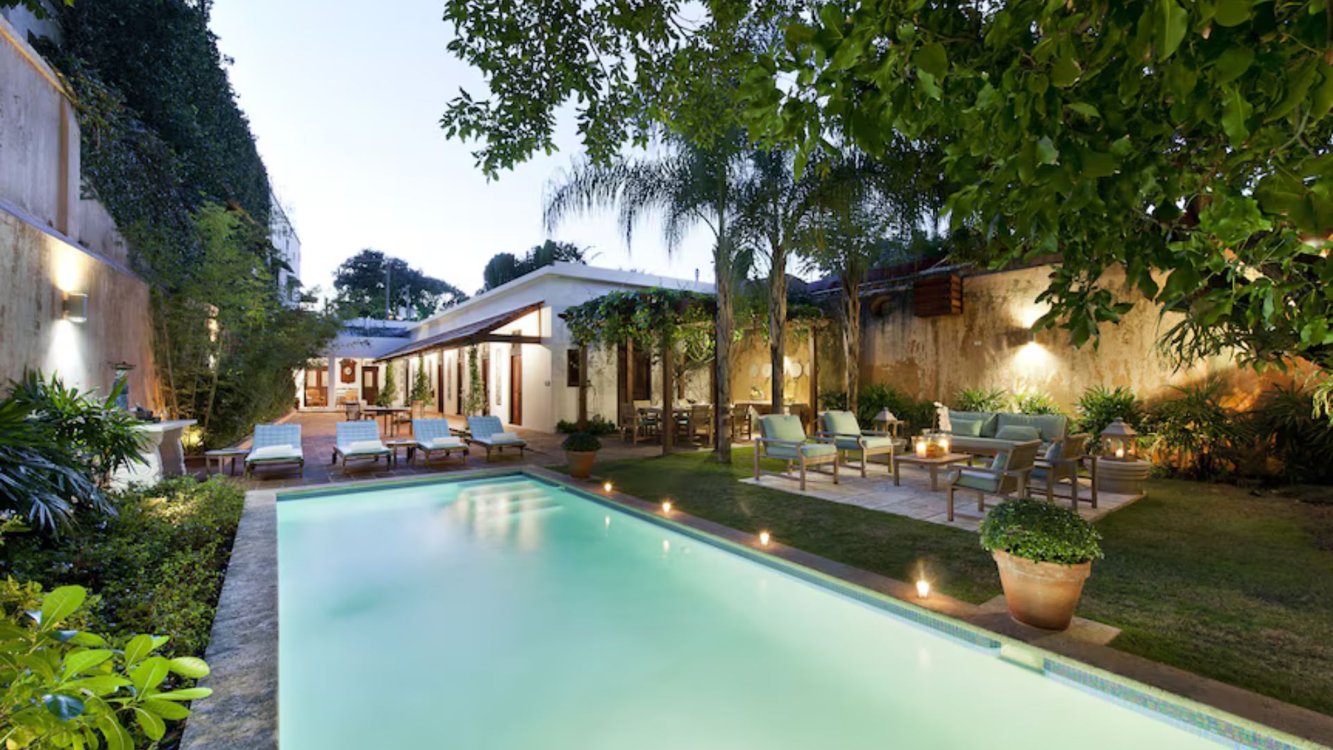 Patio exterior con piscina pequeña y área lounge iluminada.