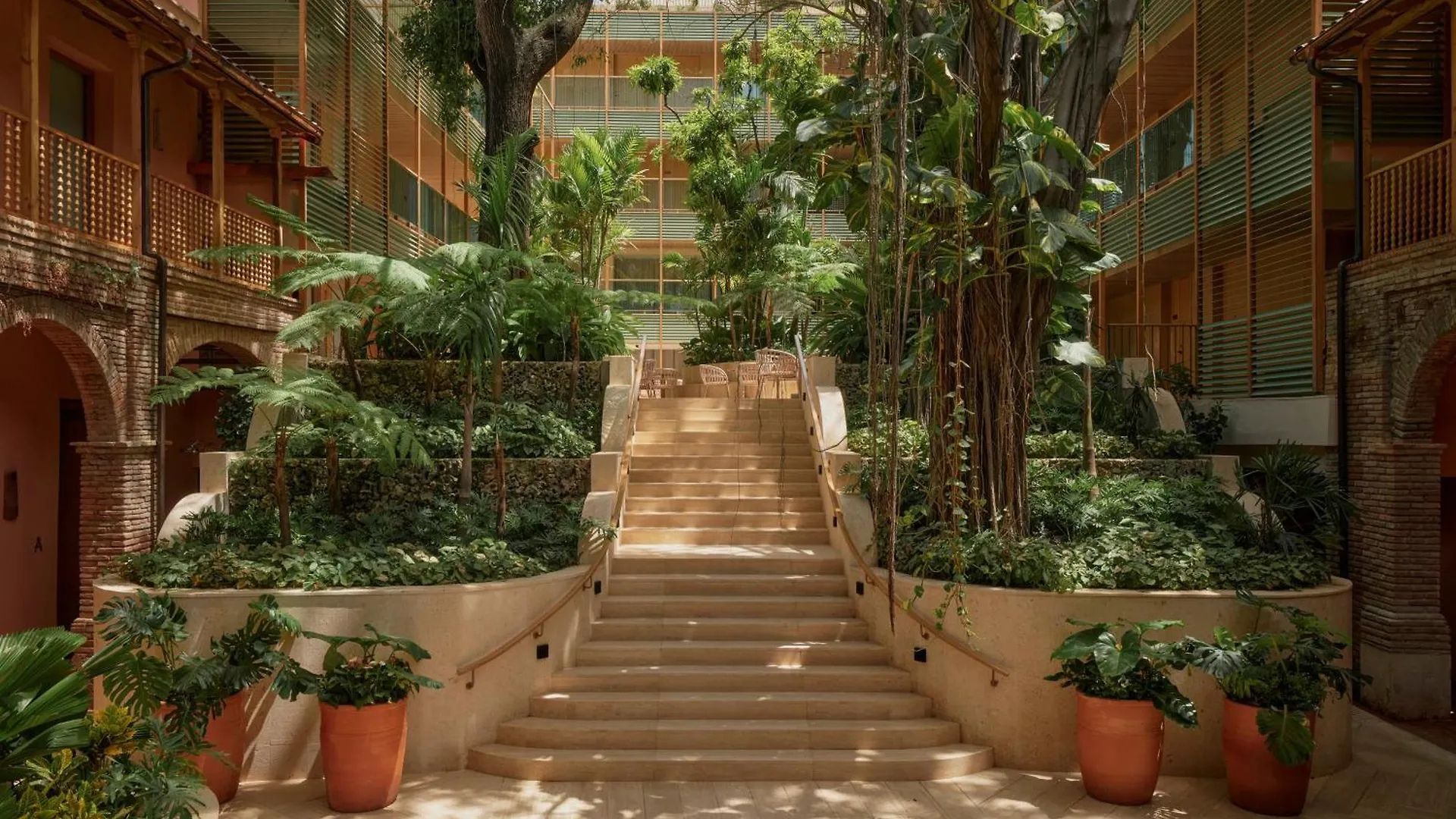 Patio interior con jardín tropical y escaleras en hotel boutique.