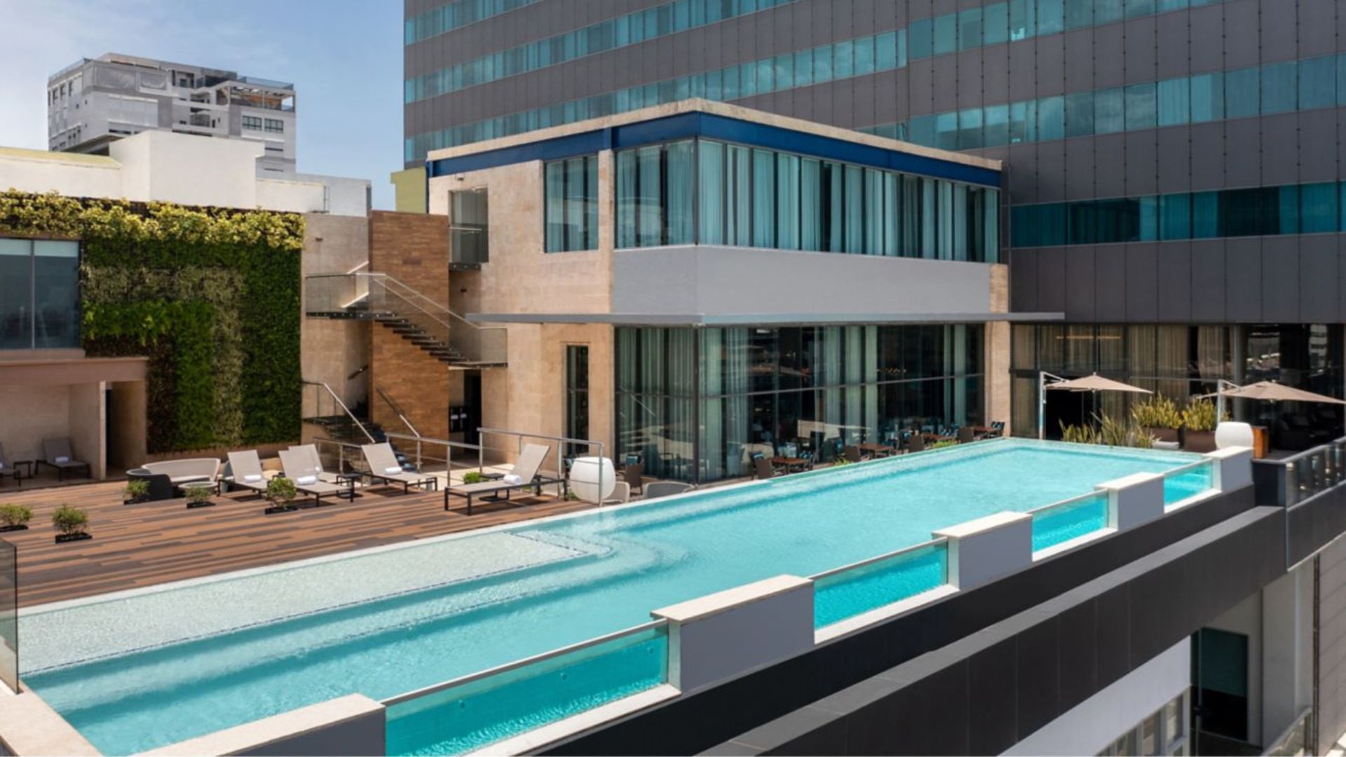 Piscina elevada en hotel moderno con terraza y área de descanso.