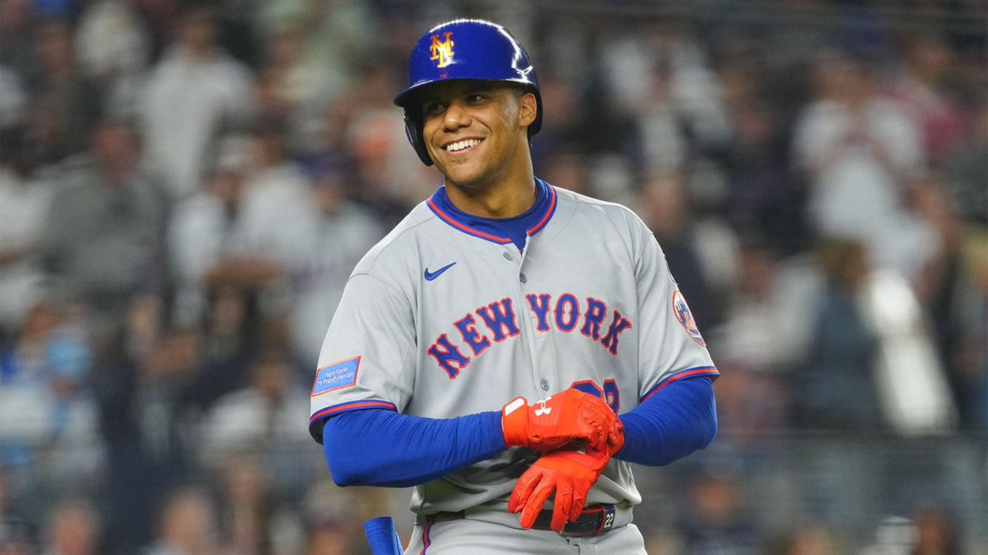 Jugador de béisbol de los Mets sonriendo en el terreno de juego durante un partido.
