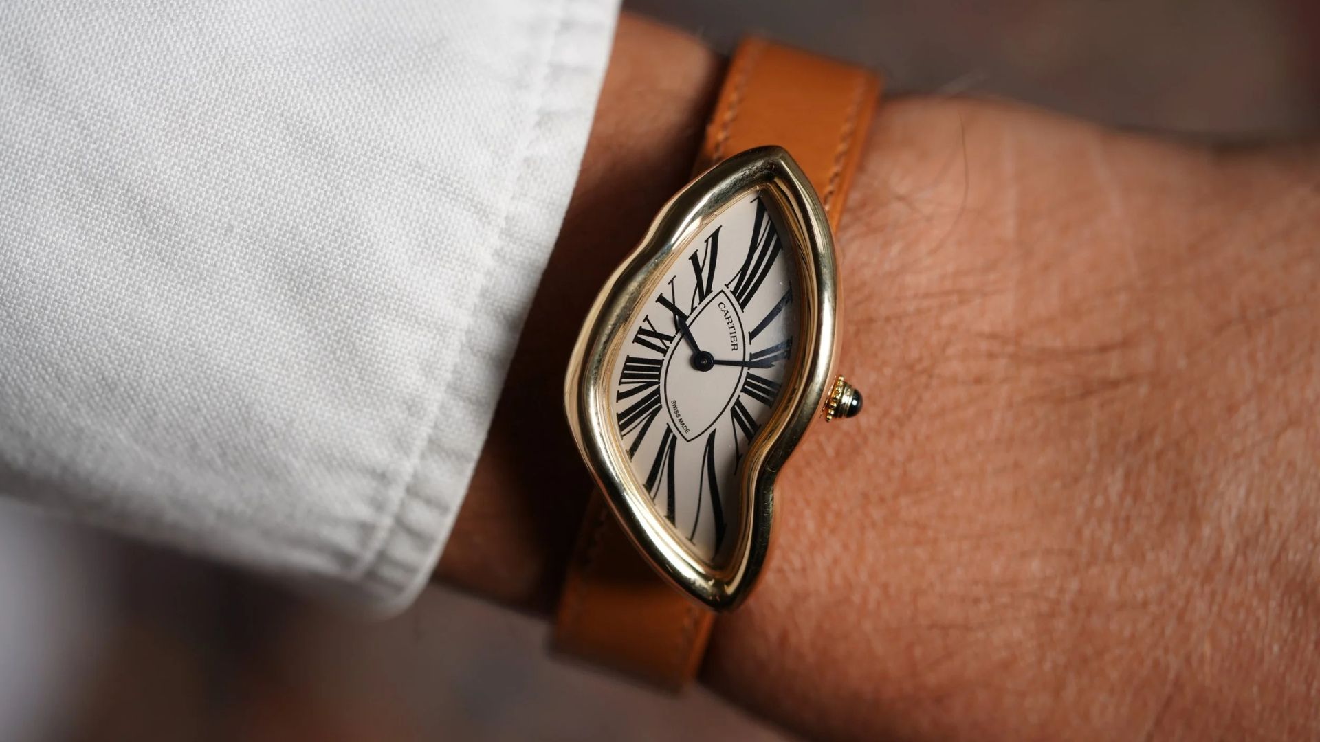 Reloj Cartier de diseño único, mostrando detalles de la esfera con números romanos.