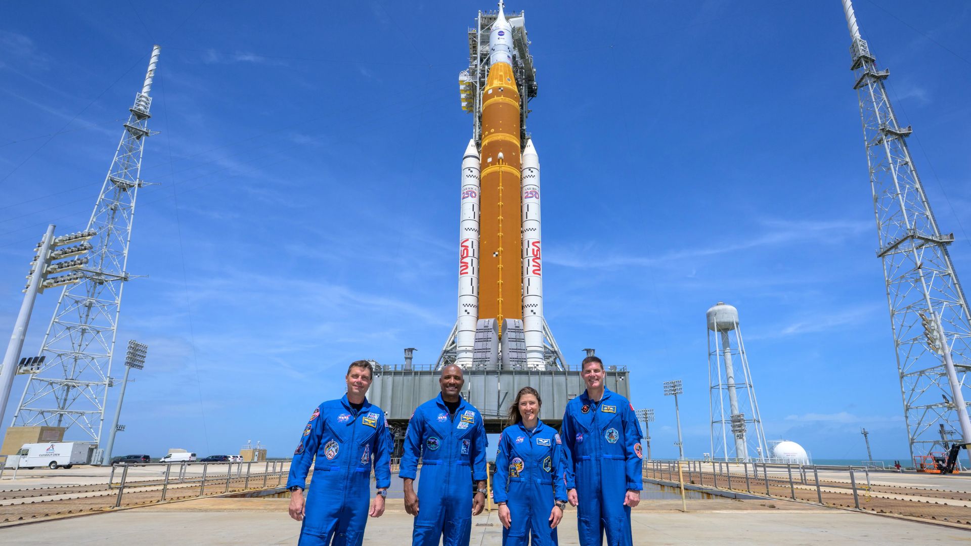 Cuatro astronautas frente a un cohete de la NASA en la plataforma de lanzamiento.
