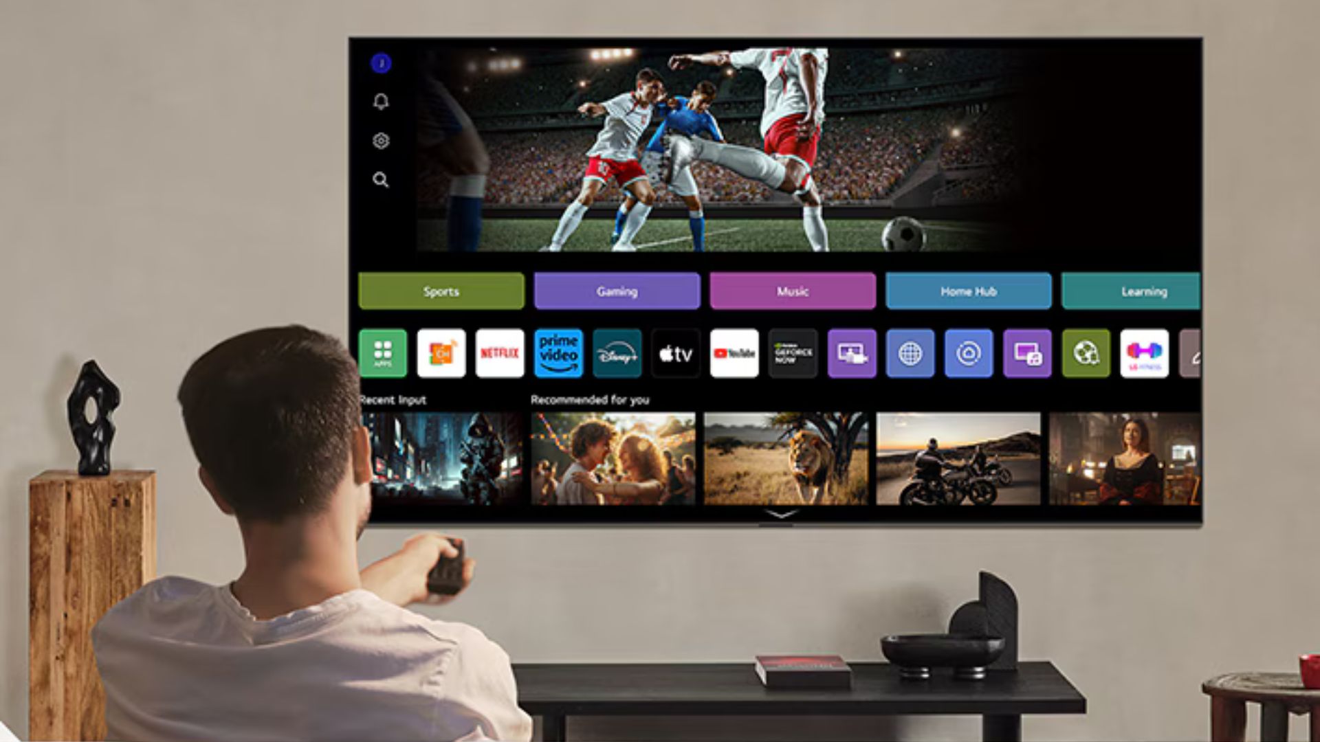 Una persona viendo la televisión con una pantalla mostrando las opciones de aplicaciones como Netflix, Prime Video, y otros servicios en un televisor moderno.