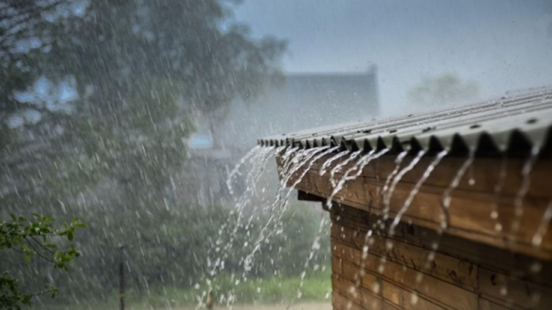 Lluvia intensa cayendo sobre el techo de una casa con agua desbordándose por el borde.