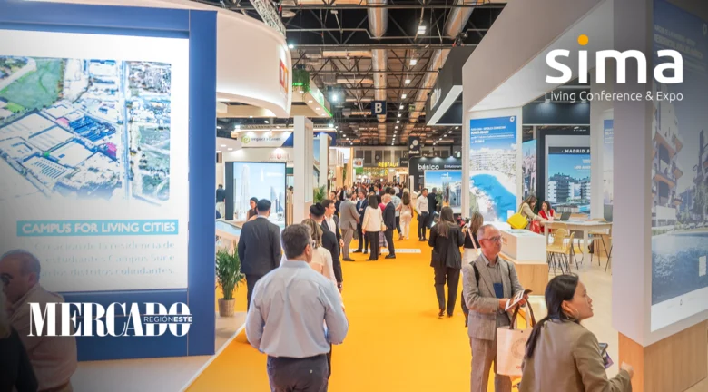 Asistentes recorren los pasillos de la feria SIMA, observando stands de diferentes expositores del sector inmobiliario.