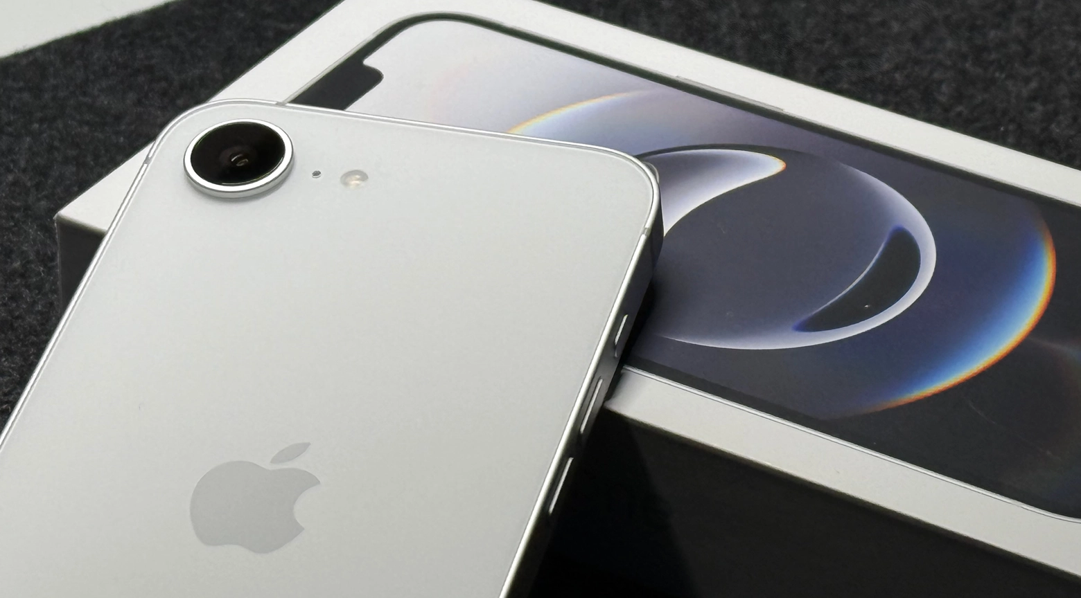 iPhone color blanco sobre su caja, mostrando la cámara trasera y el logotipo de Apple.