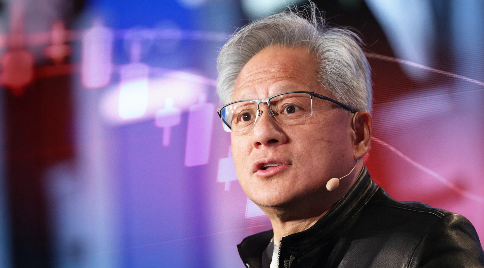 Primer plano de Jensen Huang, CEO de Nvidia, usando un micrófono de diadema mientras explica la caída reciente de acciones de empresas de inteligencia artificial, con gráficos financieros difuminados al fondo.