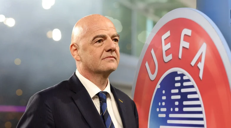 Un dirigente del fútbol posa junto al logotipo de la UEFA durante un evento oficial.