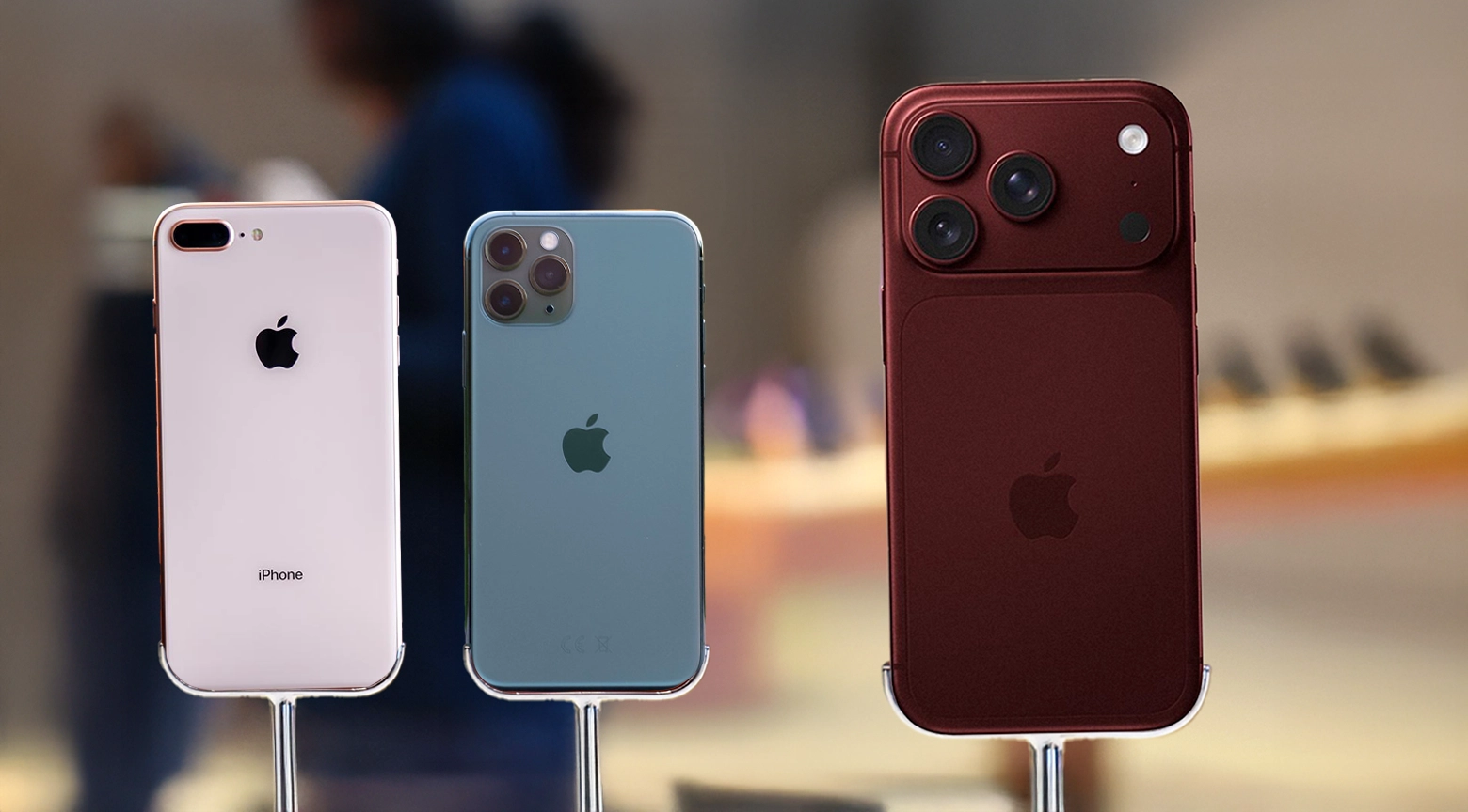 Tres modelos de iPhone de distintas generaciones se exhiben sobre soportes, mostrando sus cámaras traseras y el diseño característico de los teléfonos de Apple.