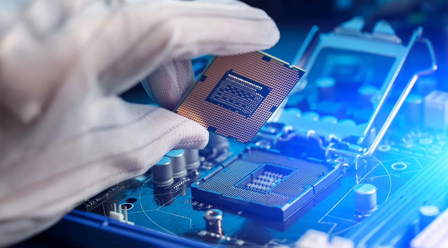 Mano con guante de protección sosteniendo un microchip sobre una placa electrónica iluminada con tonos azules.