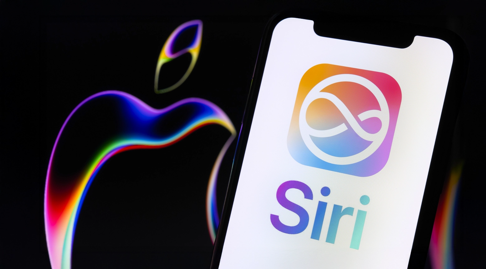 Imagen de un iPhone con el logotipo de Siri en pantalla, junto al logo de Apple iluminado con efectos de colores sobre un fondo oscuro.
