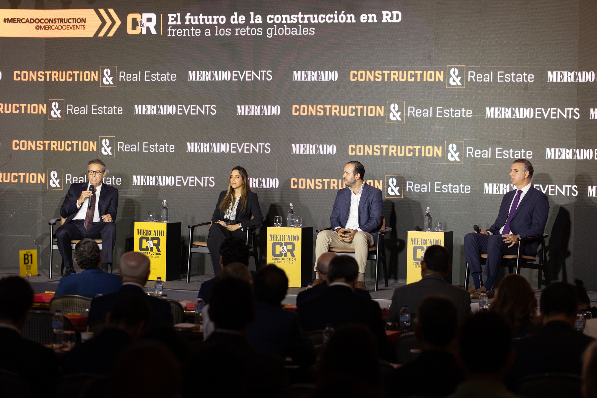Panel de expertos durante un evento sobre el futuro de la construcción en República Dominicana, con cuatro participantes sentados frente a un público.
