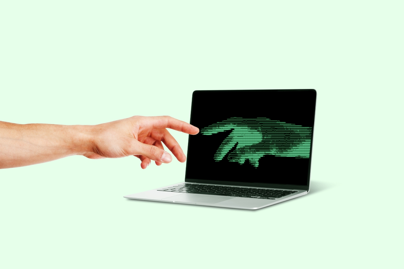 Mano humana acercándose a una mano digital verde representada en la pantalla de una computadora portátil, ilustrando la intimidad artificial y la interacción entre personas y chatbots de IA.