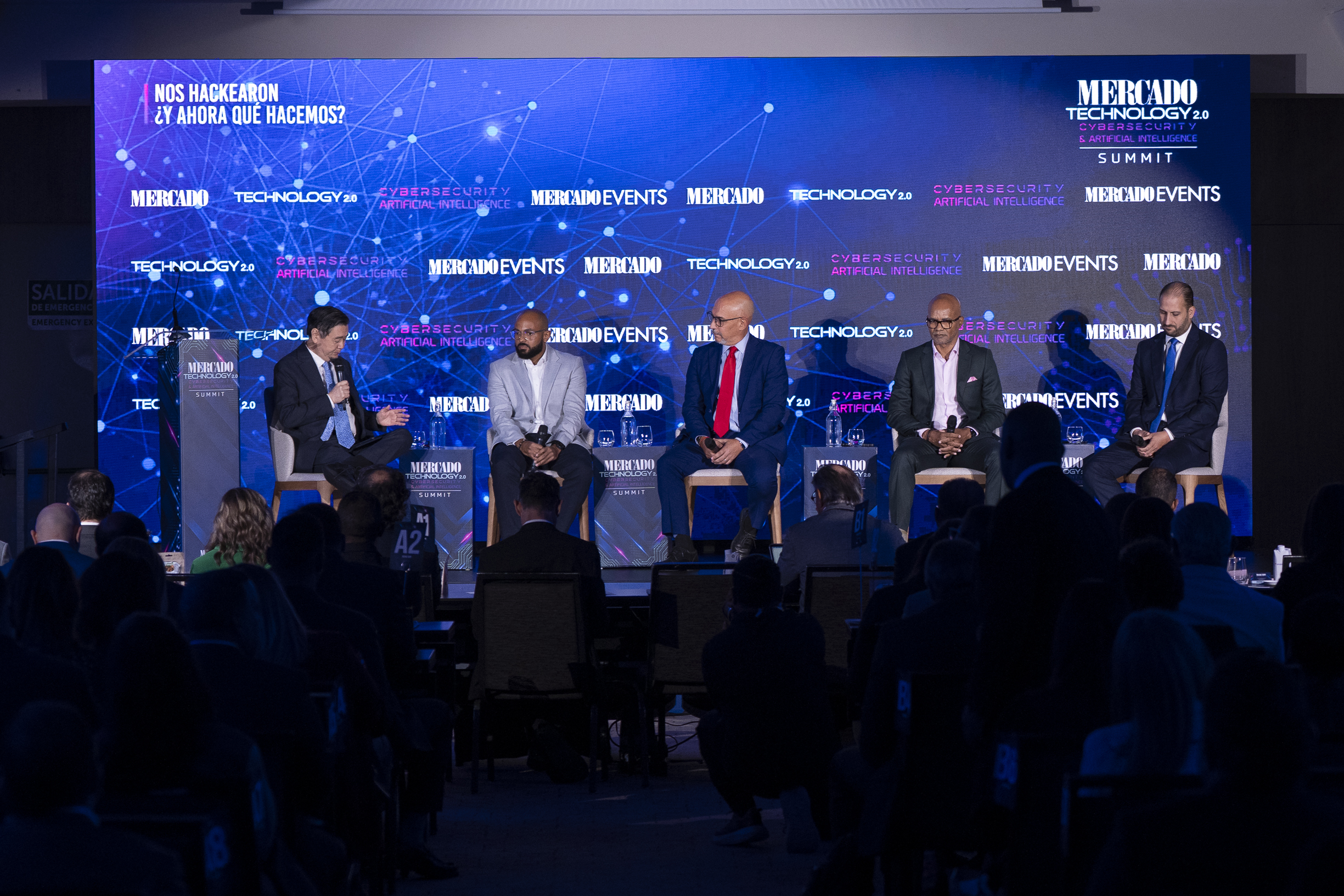 Cinco especialistas participan en un panel sobre ciberseguridad durante el Mercado Technology 2.0 Summit. Uno de los expositores habla por un micrófono mientras los demás escuchan, frente a una audiencia de profesionales.