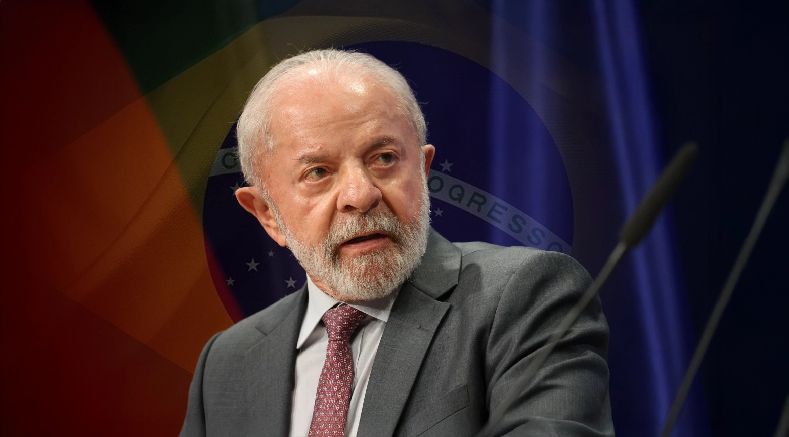 El presidente de Brasil, Luiz Inácio Lula da Silva, con expresión seria frente a un micrófono y con la bandera nacional de Brasil detrás.