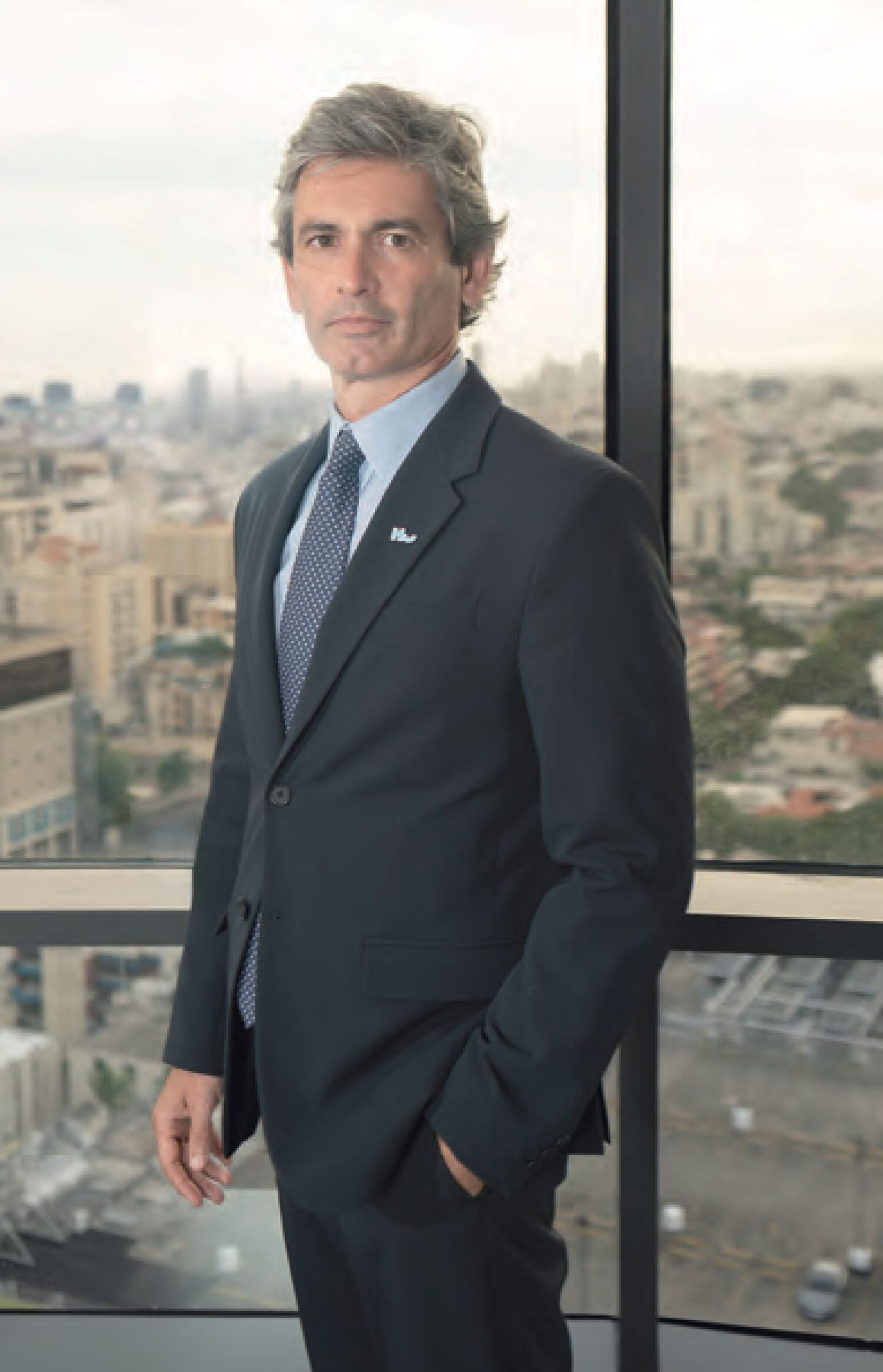 Carlos Mitnik, vicepresidente ejecutivo-gerente general de Humano Seguros, posa frente a un ventanal con vista panorámica de Santo Domingo.